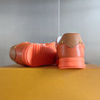 Orange sneakers with white laces, back view showing treaded orange sole