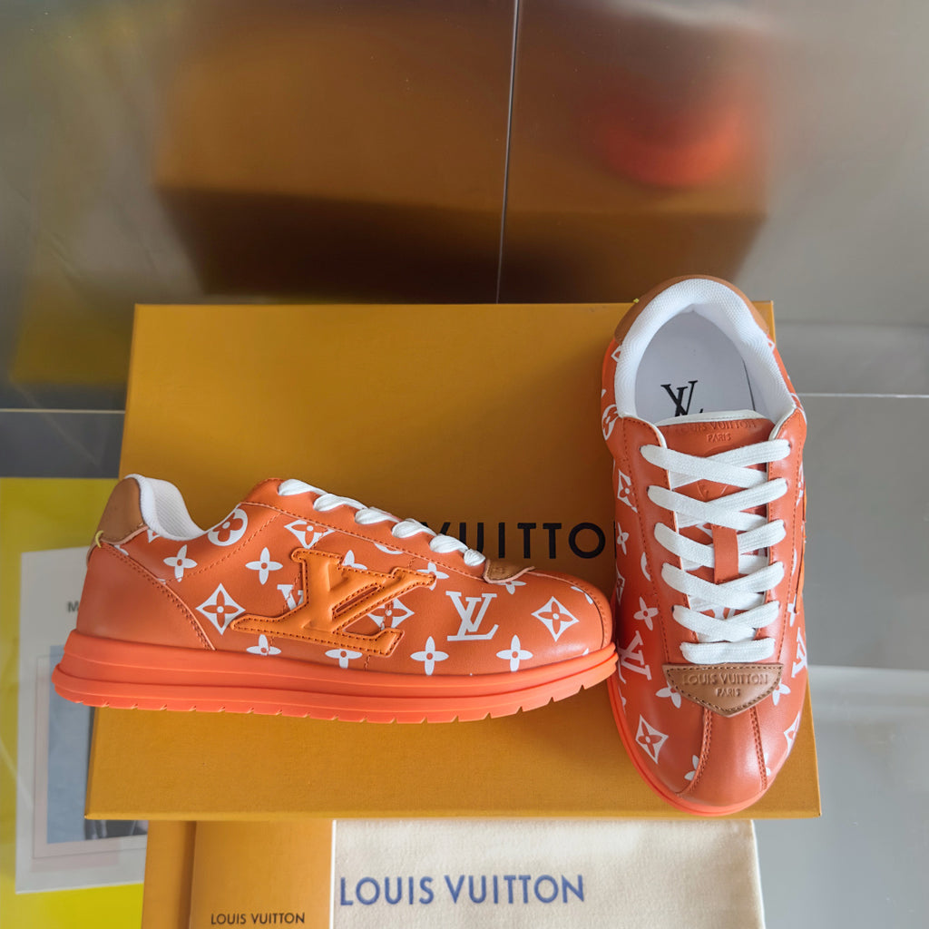 Orange monogram sneakers with white laces and chunky orange sole, one shoe front