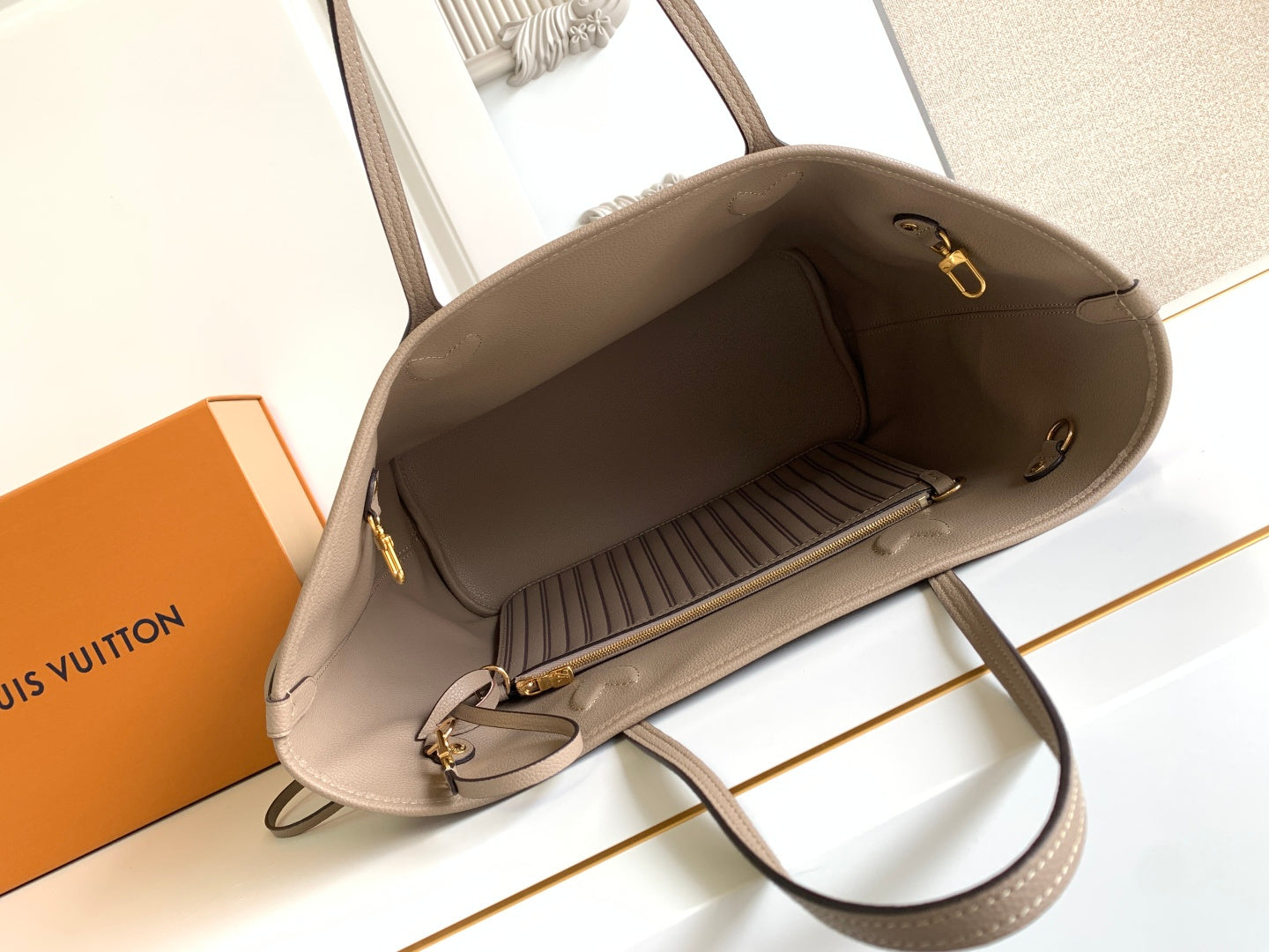 Beige tote bag with top zipper and fabric-lined interior, shown open