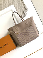 Beige monogram tote bag with light striped front panel, top handles, and gold hardware