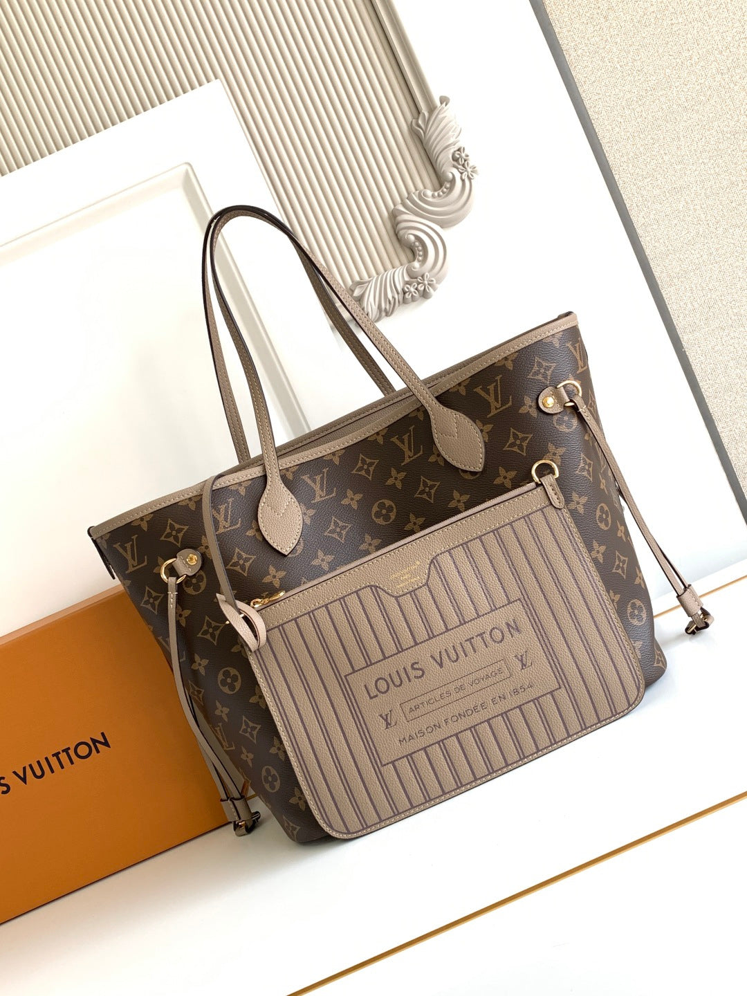 Brown monogram tote bag with light striped front panel, top handles, and zipper