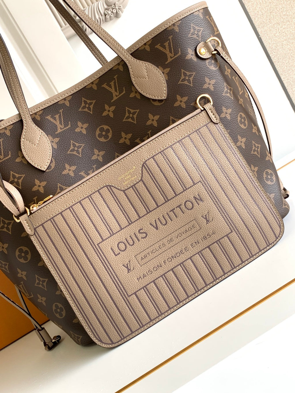 Brown monogram tote bag with beige striped front panel and zipper top closure