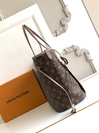 Dark monogram tote bag with long top handles, shoulder strap, and gold hardware