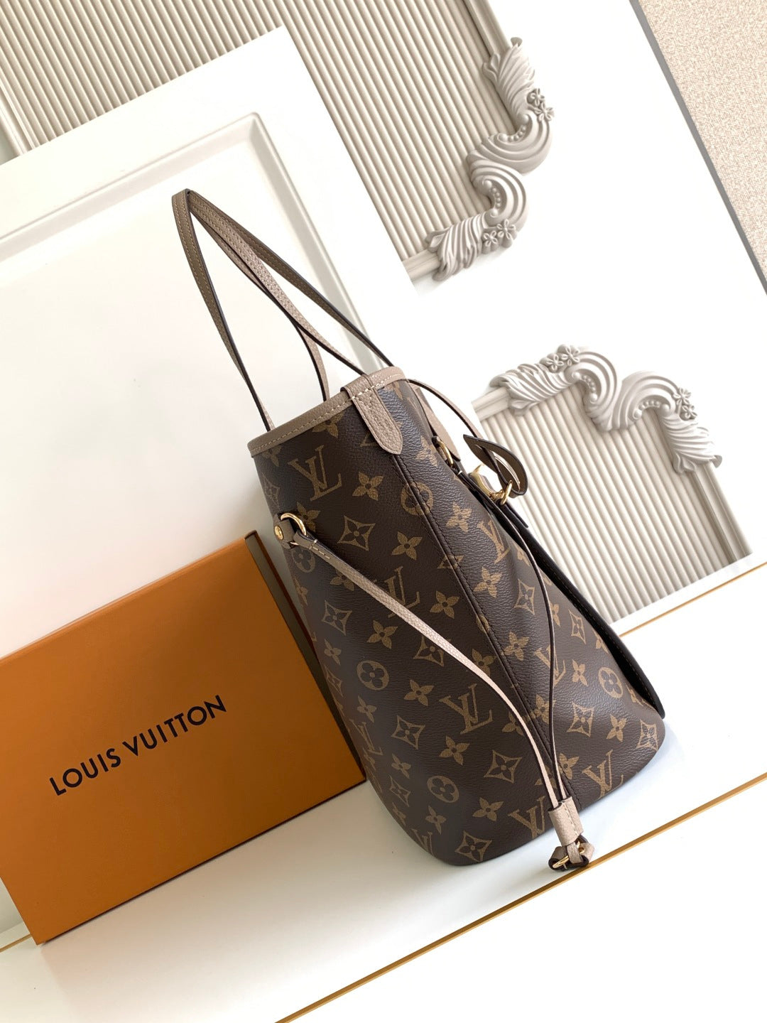 Dark monogram tote bag with long top handles, shoulder strap, and gold hardware