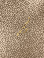 Beige textured leather fabric with small embossed logo and gold-toned accents