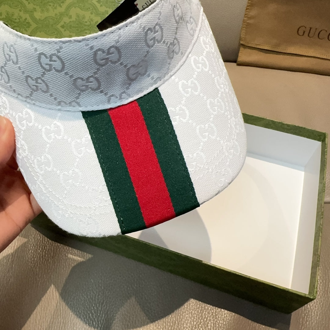 Gucci visor cap close-up: GG pattern and green red web stripe on light blue