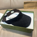 Gucci visor cap in dark monogram canvas, top view with adjustable strap and tags.