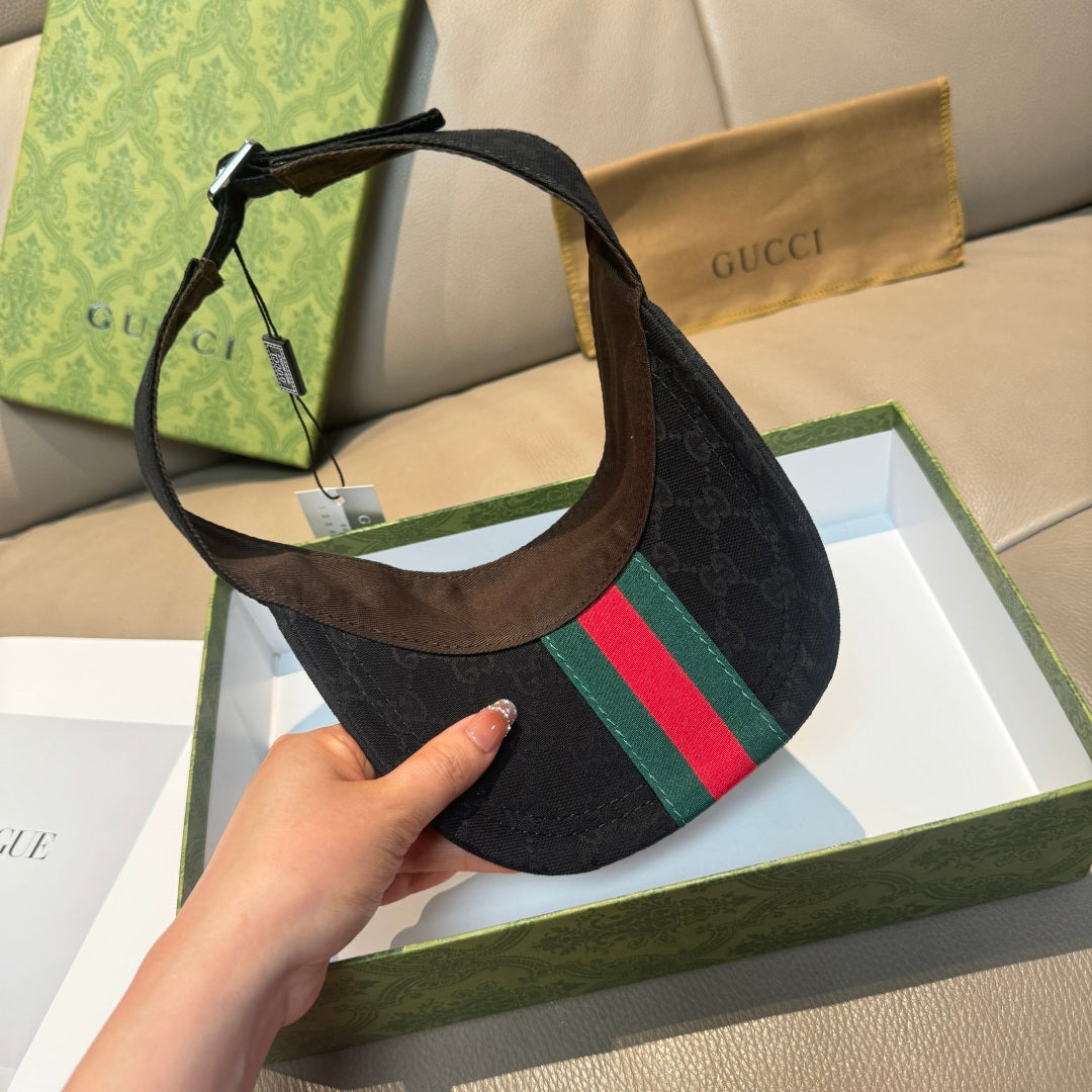 Gucci visor cap with dark monogram and green-red stripe, angled view with hanging tag.