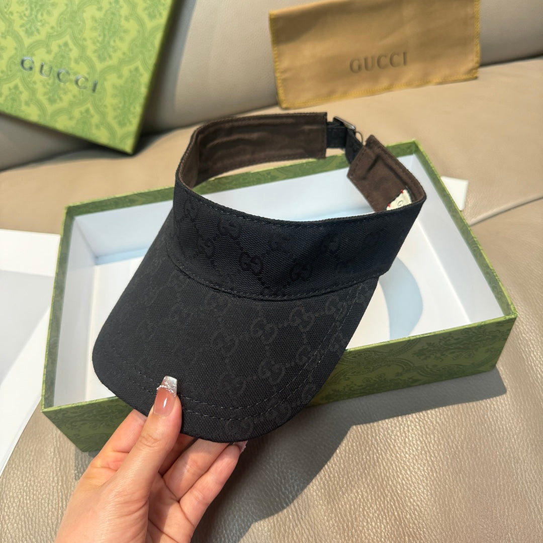 Gucci visor cap in dark monogram canvas, visible side strap and brown lining.