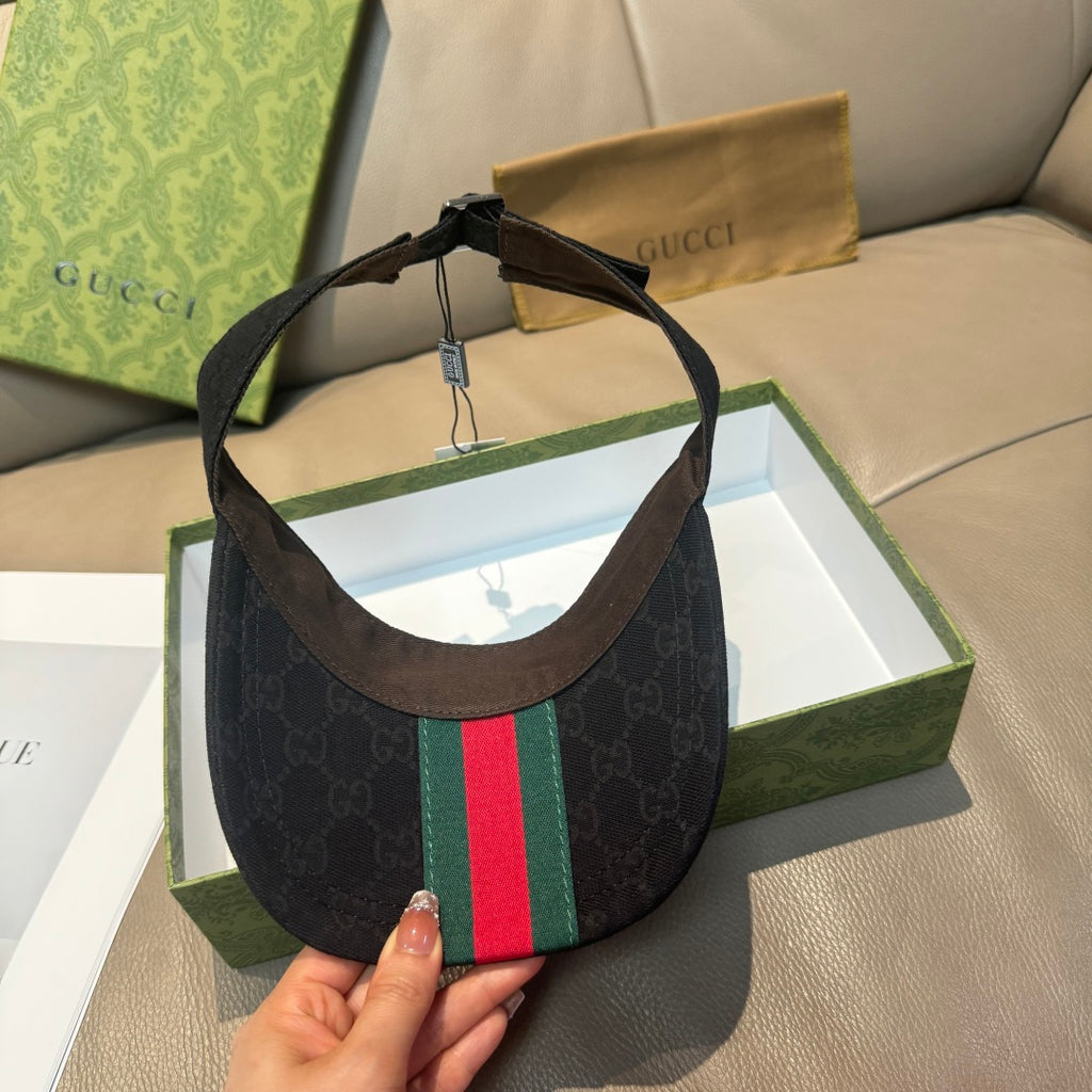 Gucci visor cap with dark monogram, green-red web stripe on side, leather-trim brim.