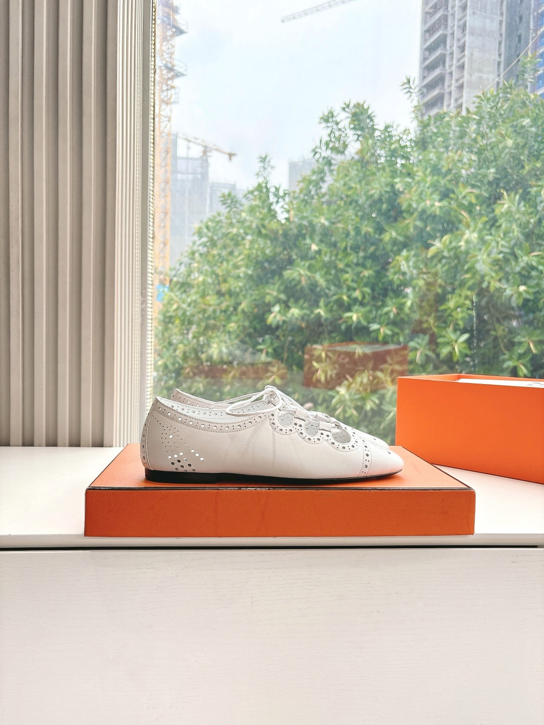 Hermes ladies white perforated lace-up shoe on display with black sole
