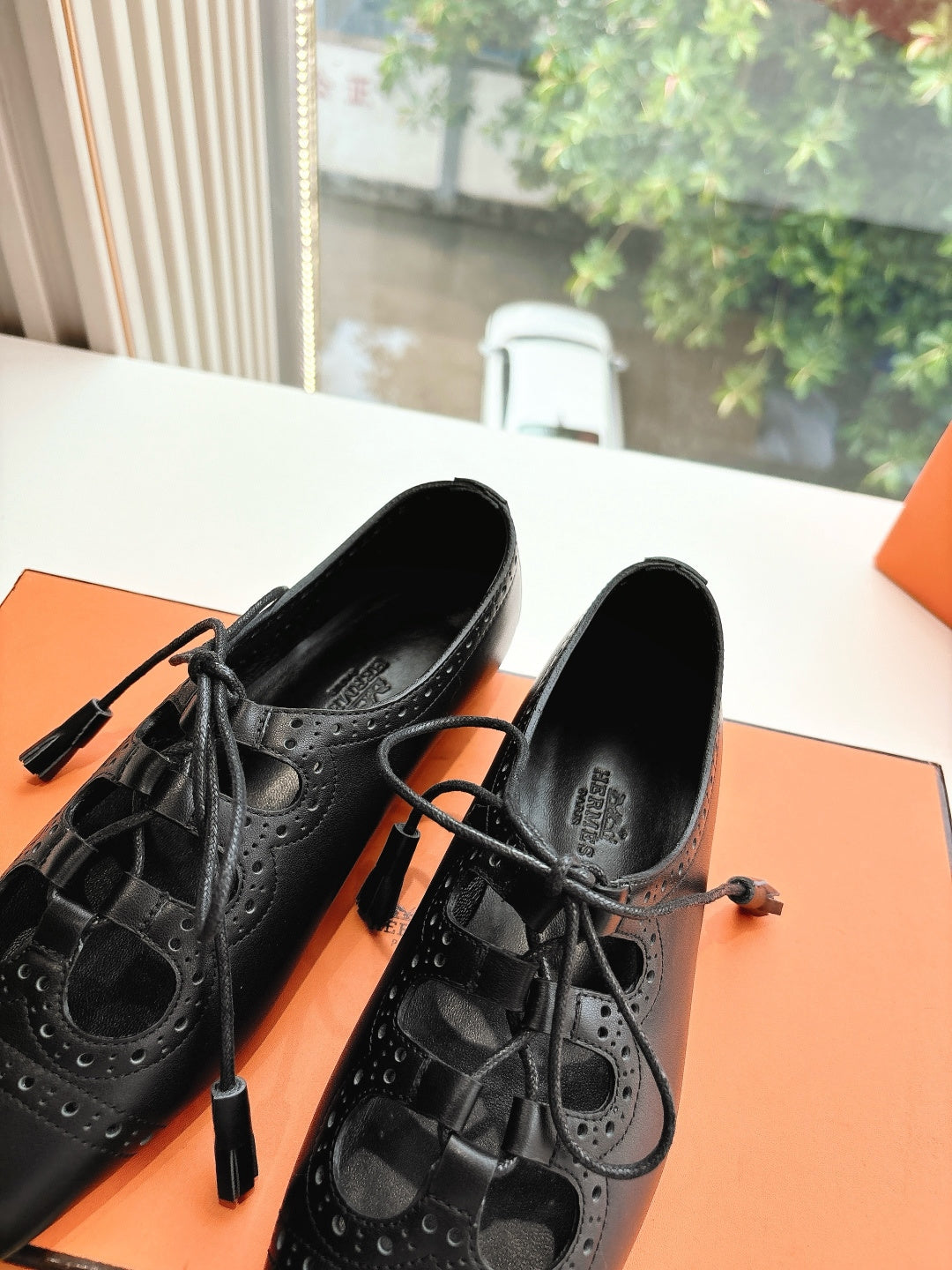 Black leather lace-up shoes with brogue-style perforations, close-up side view