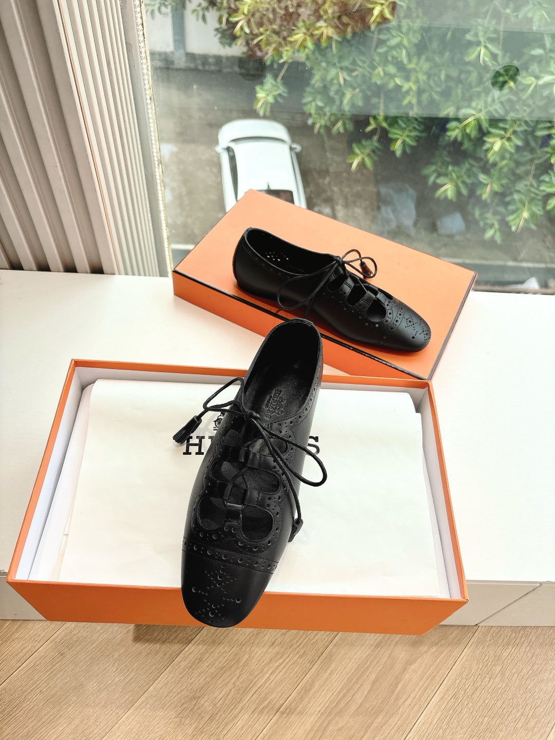 Black leather lace-up shoes with brogue-style perforations, pair on display
