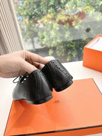 Black leather lace-up shoes with brogue-style perforations, heel close-up in hand