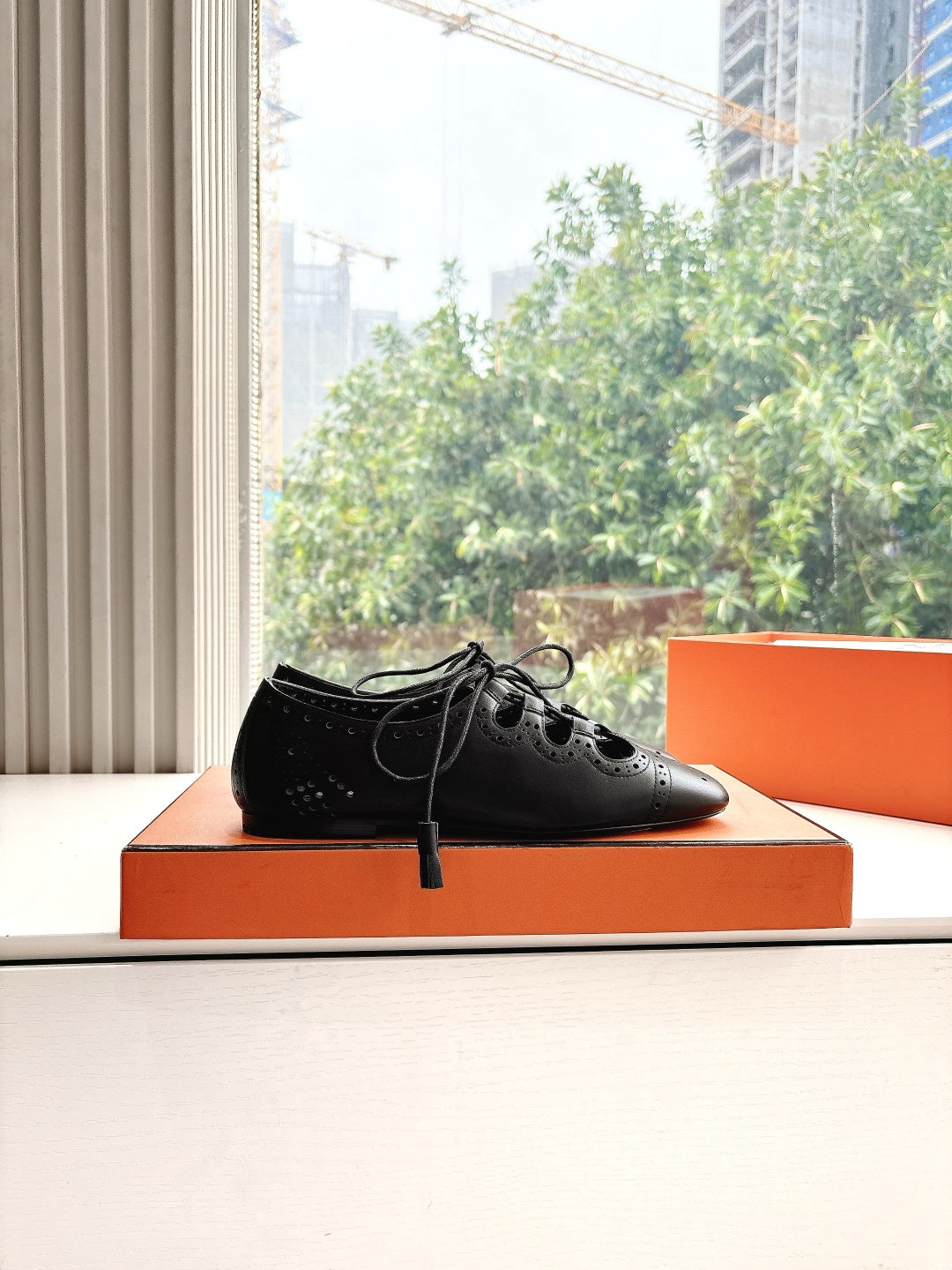 Black leather lace-up dress shoes with brogue-style perforations, single shoe view