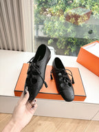 Black leather lace-up high-heel shoes with brogue-style perforations, pair view