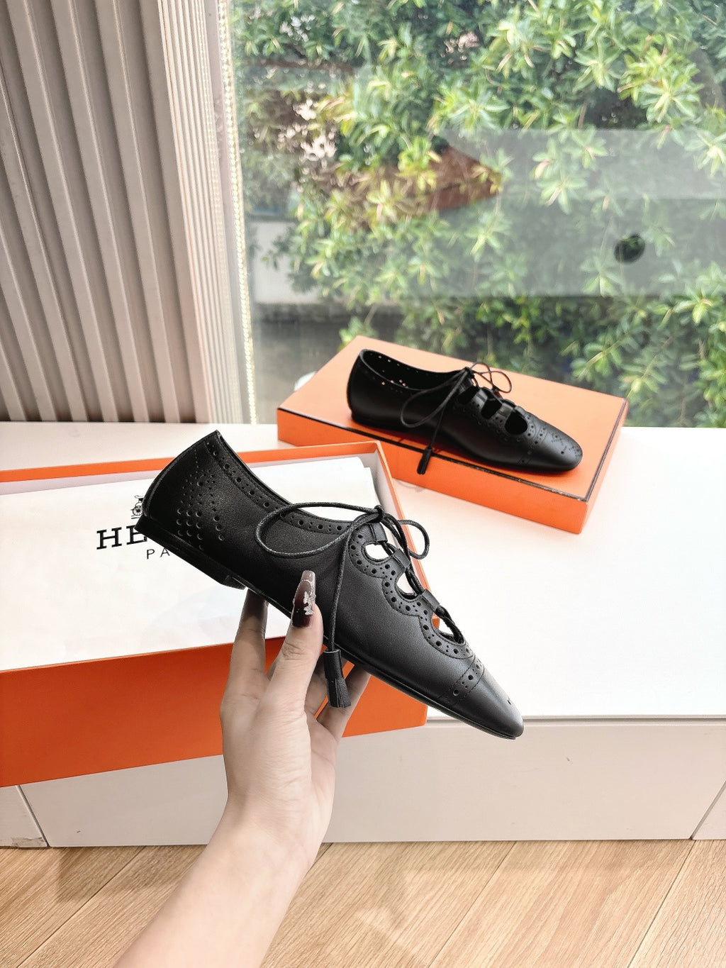 Black leather lace-up dress shoes with brogue-style perforations, held in hand