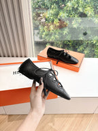 Black leather lace-up dress shoes with brogue-style perforations, held in hand
