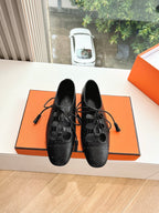 Black leather lace-up dress shoes with brogue-style perforations, front view pair