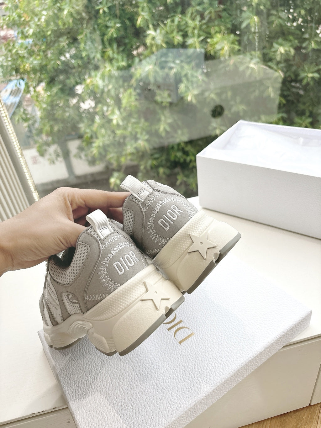 Women’s sneakers back view in light gray with Dior branding and star detail on heel