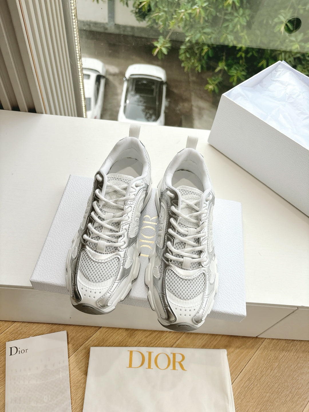 Dior women's white sneakers with lace-up front and chunky sole, resting on a box