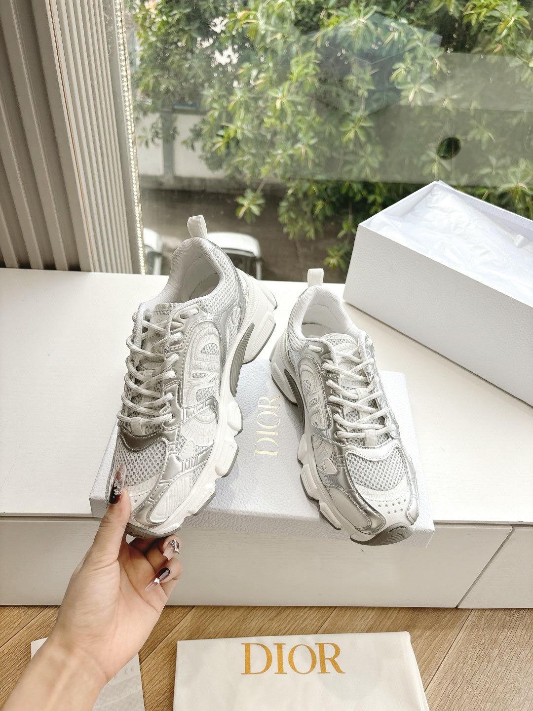 Dior women's white lace-up sneakers with textured design details, held in-hand