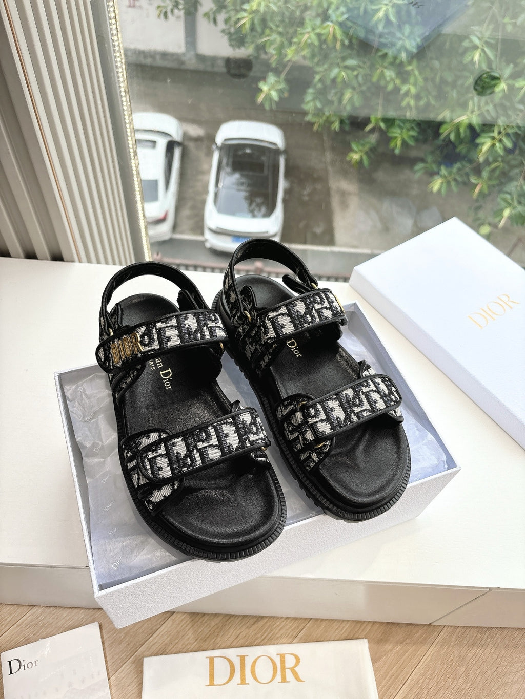 Black Dior slide sandals with patterned monogram straps and adjustable buckle