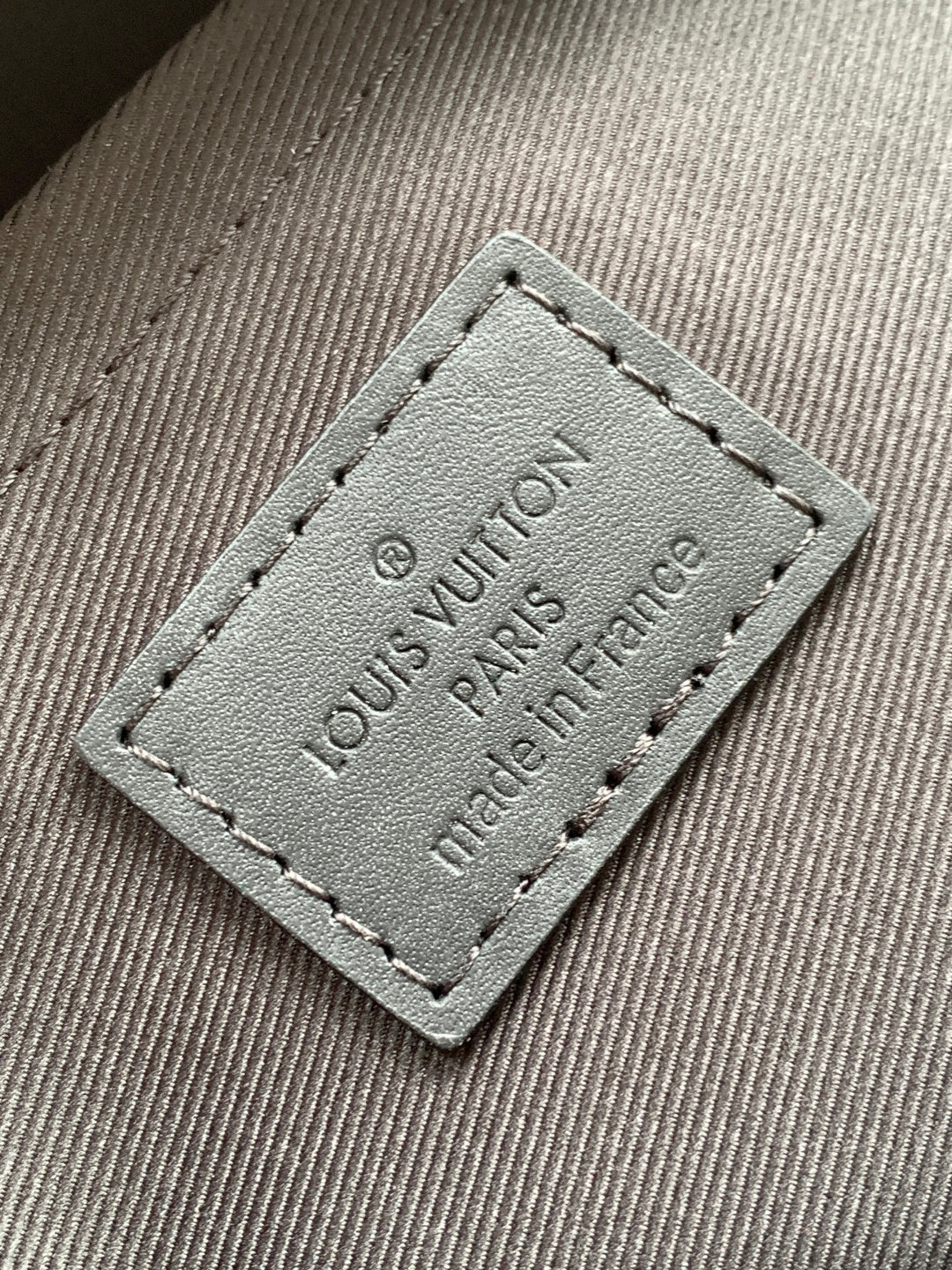 Louis Vuitton fabric label patch reading "Louis Vuitton Paris France" on gray lining