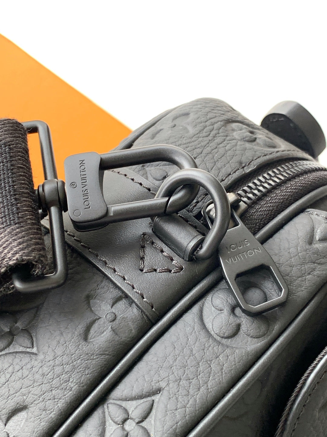 Louis Vuitton monogram crossbody bag closeup in gray with metal rings and strap adjuster