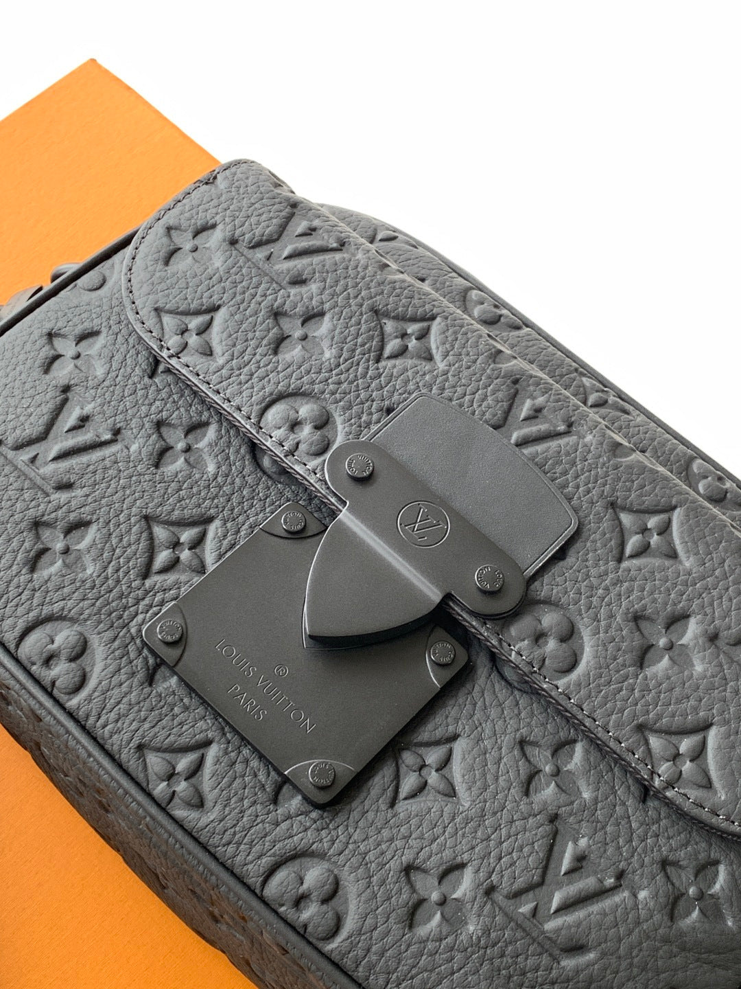 Louis Vuitton monogram bag closeup in gray with snap hardware and embossed logo pattern
