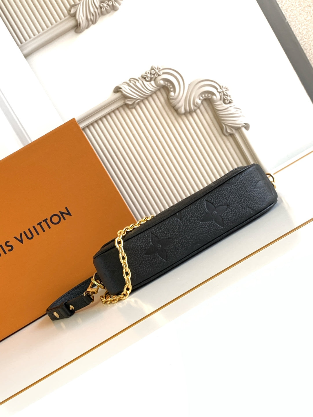 Black embossed flap shoulder bag with gold chain strap and front closure button