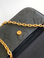 Close-up of black leather flap bag with gold chain and round snap button