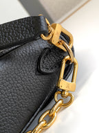 Close-up of black leather bag clasp with gold hardware and chain strap