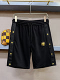 Black drawstring shorts with gold emblem and side logo accents