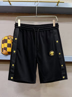 Black drawstring shorts with gold emblem and side logo accents