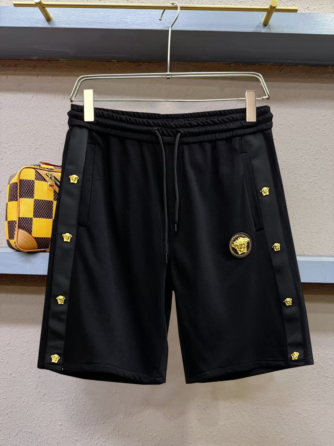 Black drawstring shorts with gold emblem and side logo accents