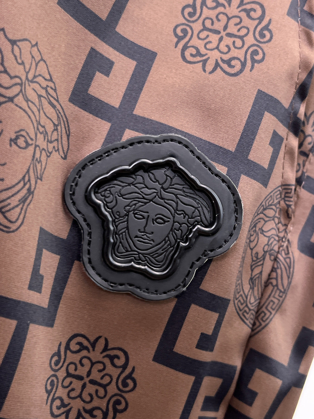Medallion applique on logo-pattern shorts leg: black patch with face emblem, on tan fabric
