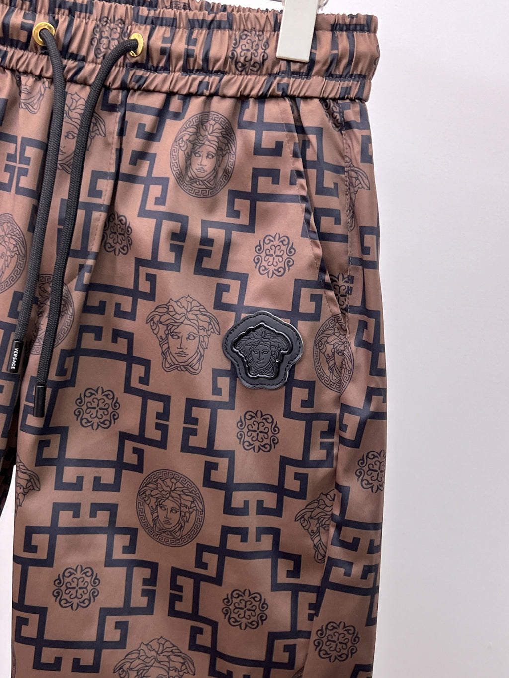 Beige shorts with navy medallion applique and scattered Greek key icons