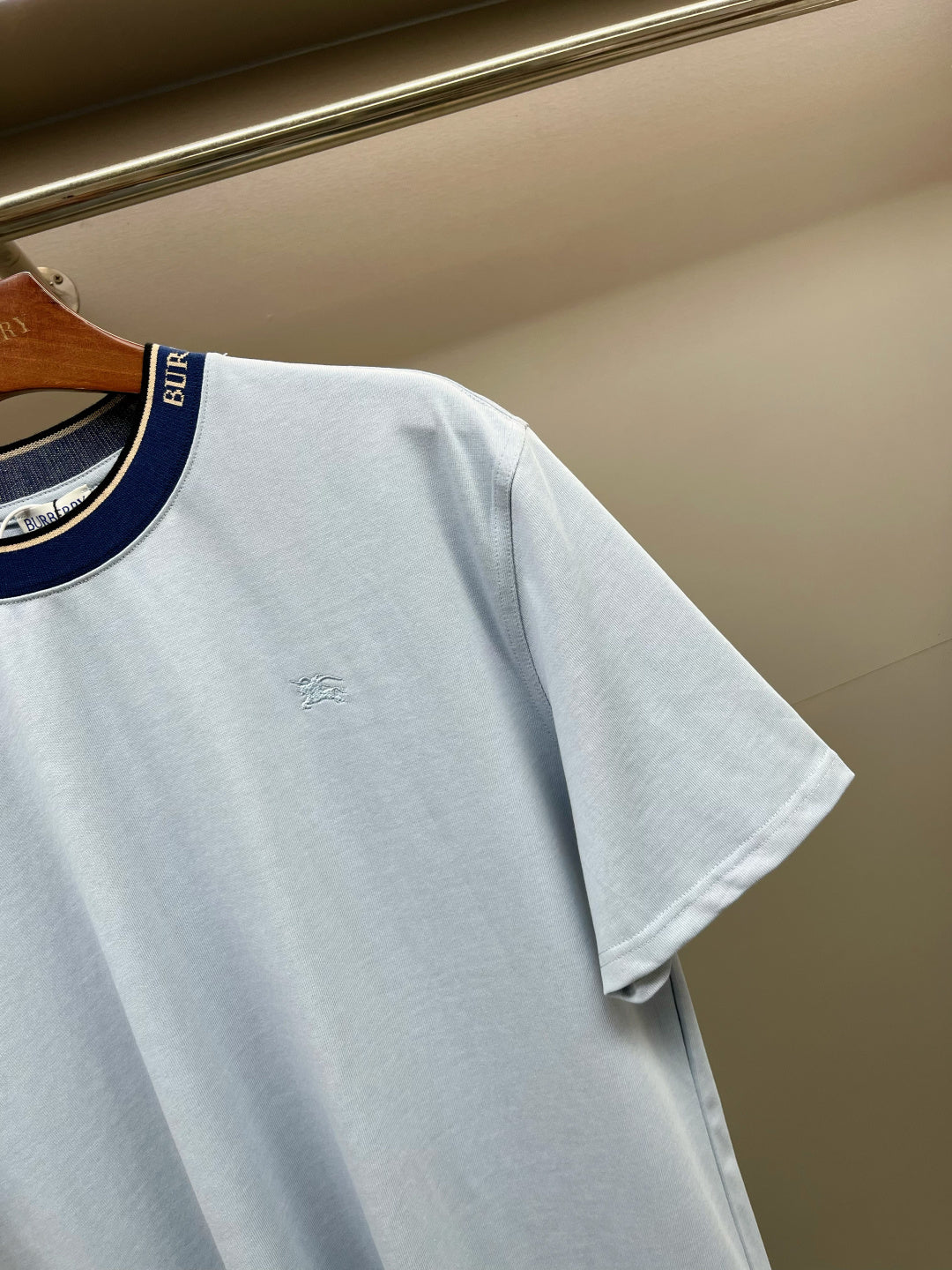 Light blue Burberry T-shirt sleeve detail with navy-trim collar and small chest logo.