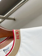 T-shirt collar edge detail: tan band with red trim and vertical Burberry lettering.