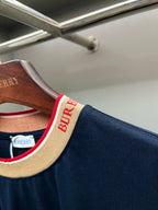 Burberry navy short-sleeve top close-up of shoulder seam and red “B” logo trim