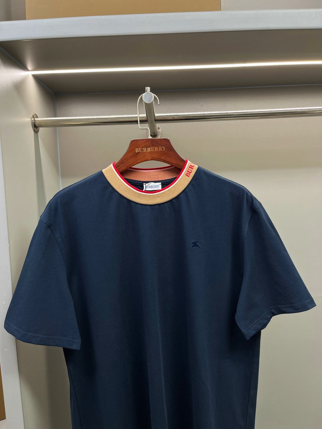 Burberry navy short-sleeve top on hanger with beige collar and red trim accents