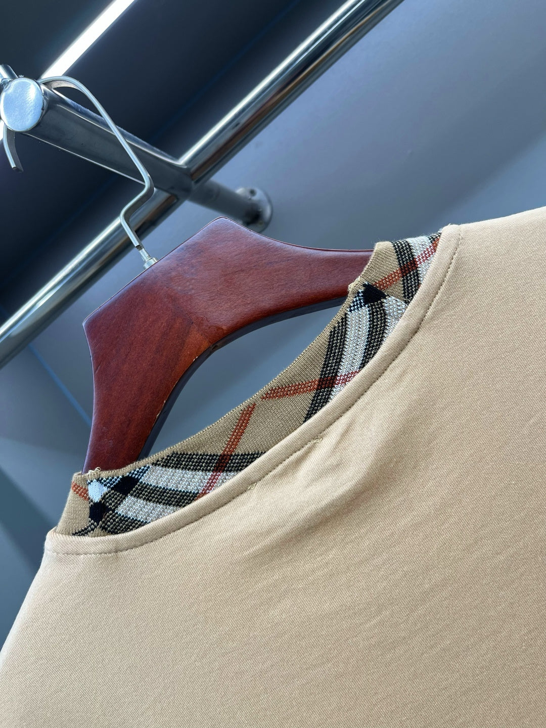 Beige T-shirt neckline close-up with plaid inner collar trim