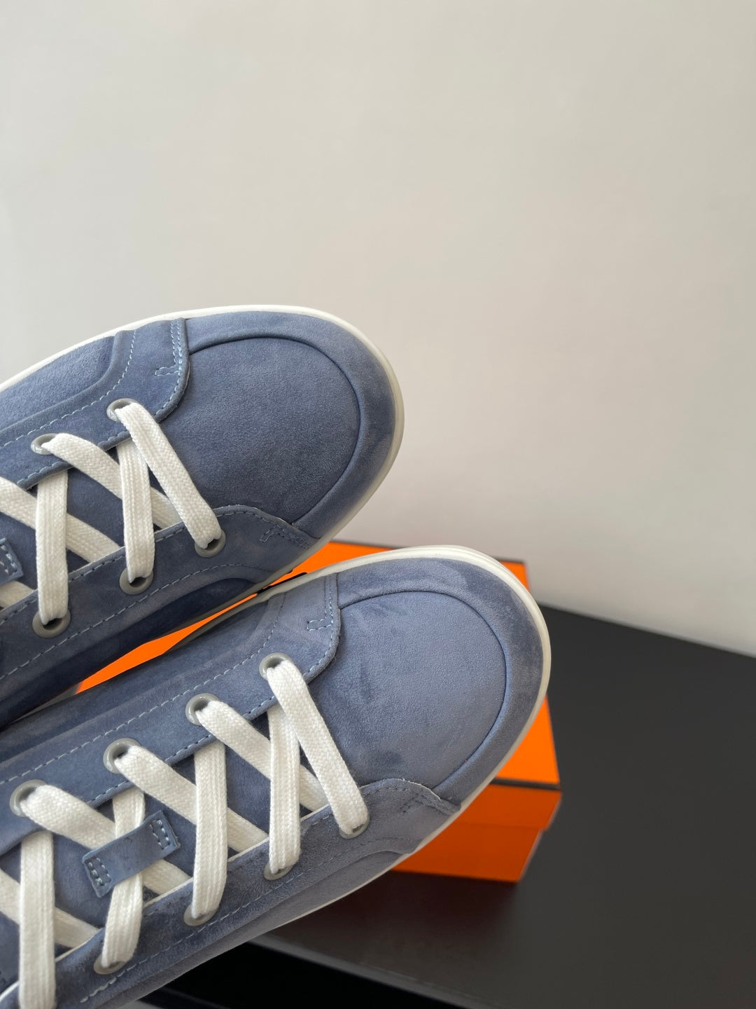 Blue suede sneaker side with white laces and stitched sole edge