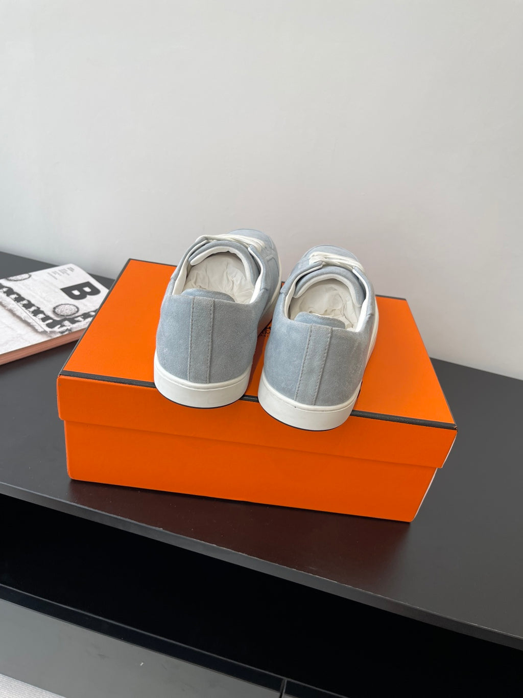 Hermes light blue sneakers shown from the back on an orange shoebox