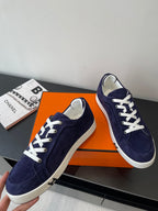 Hermes women's navy suede sneakers with white laces and white sidewall, angled view