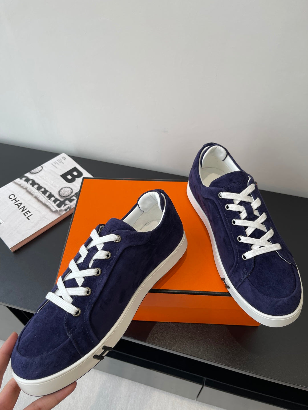 Hermes women's navy suede sneakers with white laces and white sidewall, angled view
