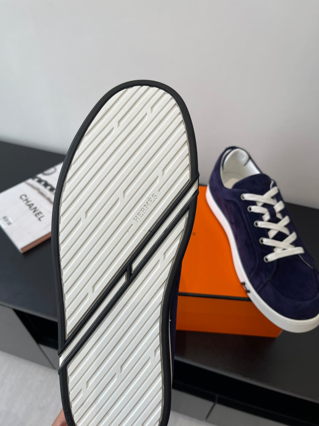 Hermes women's sneaker outsole view with navy shoe and white ribbed traction sole