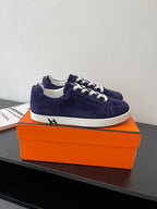 Hermes women's low-top sneakers in navy suede with white lace-up; side view