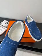 Blue denim slip-on shoes with white interior lining and stitched side seams.